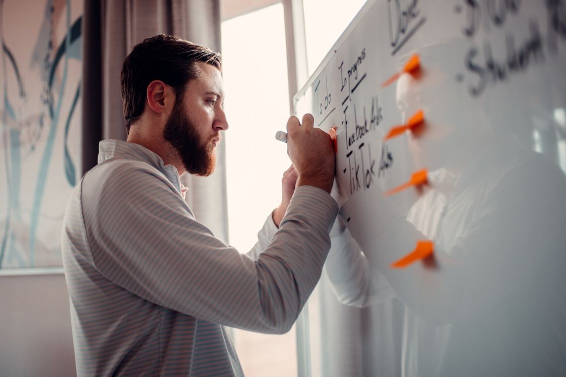 Mann, der auf ein Whiteboard schreibt