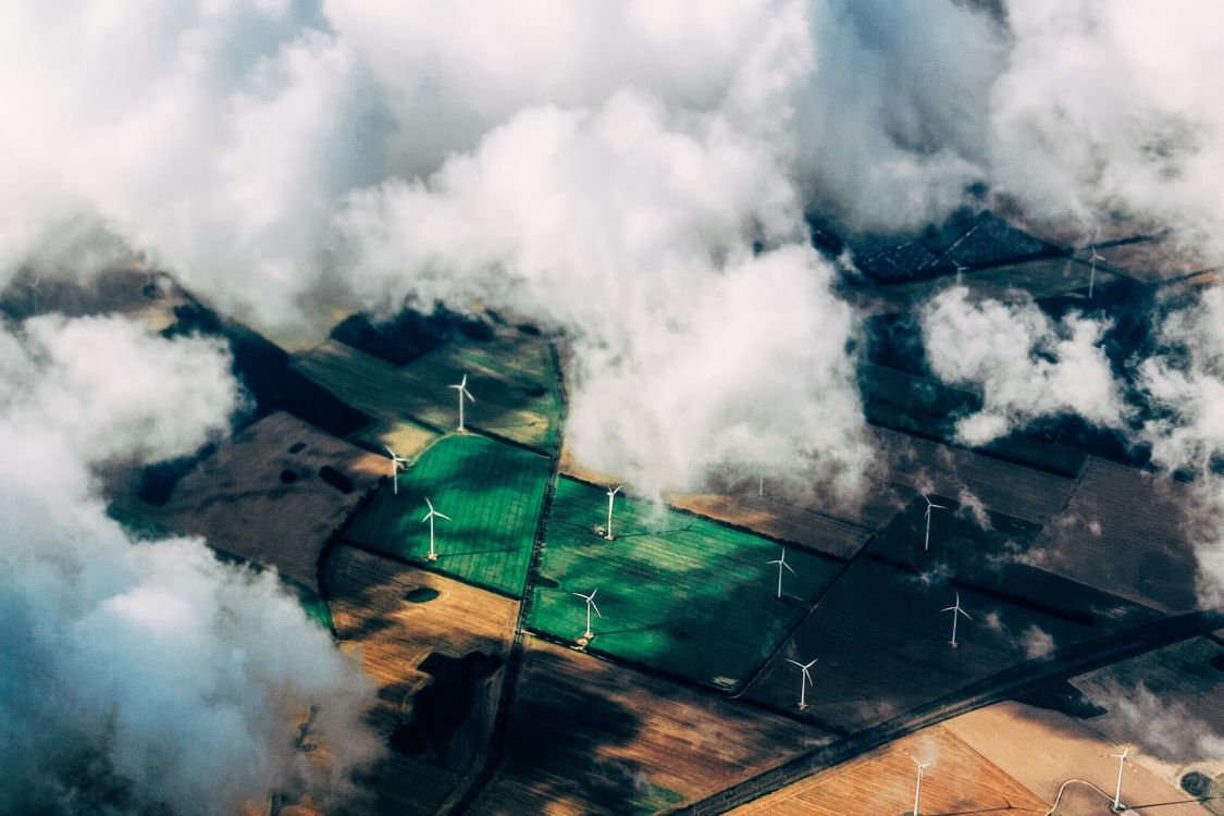Landschaft mit Windrädern aus Vogelperspektive, teils durch Wolken verdeckt