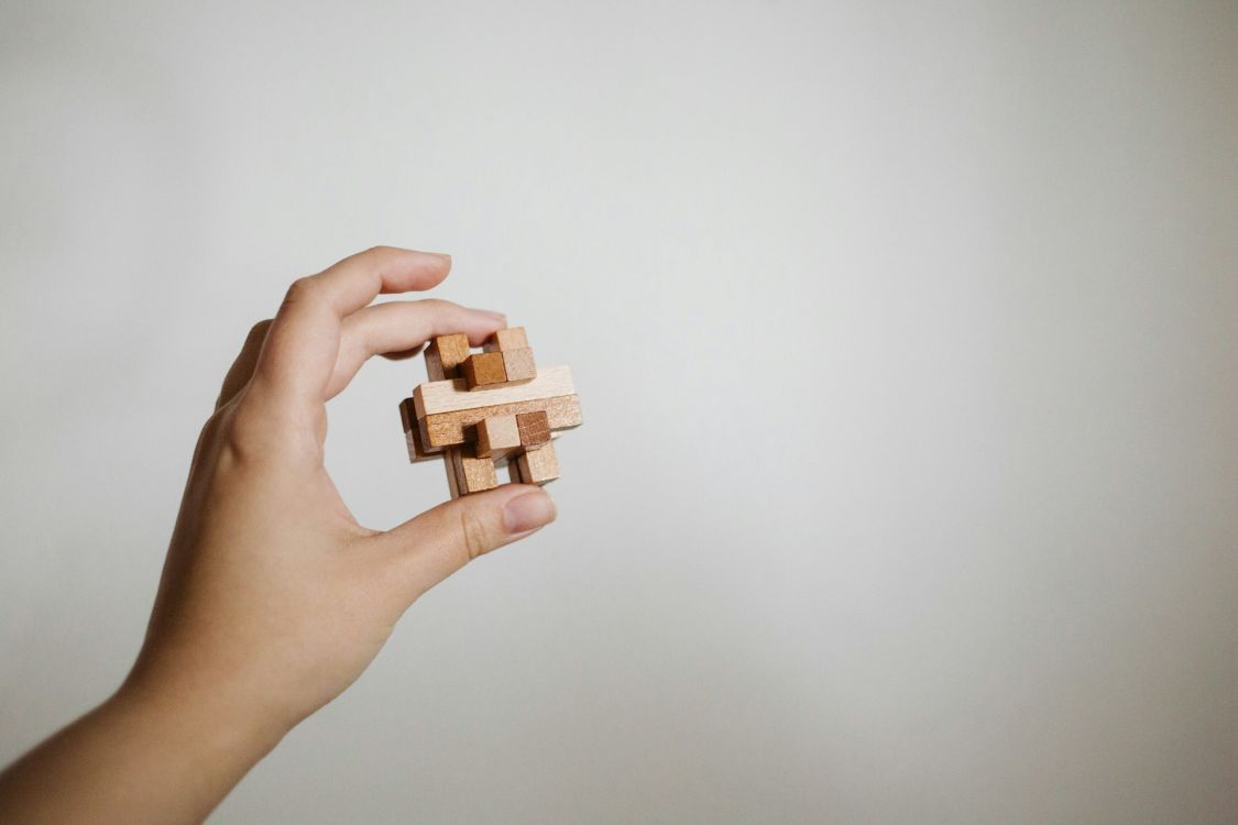 Hand hält ein Holzpuzzle in die Höhe