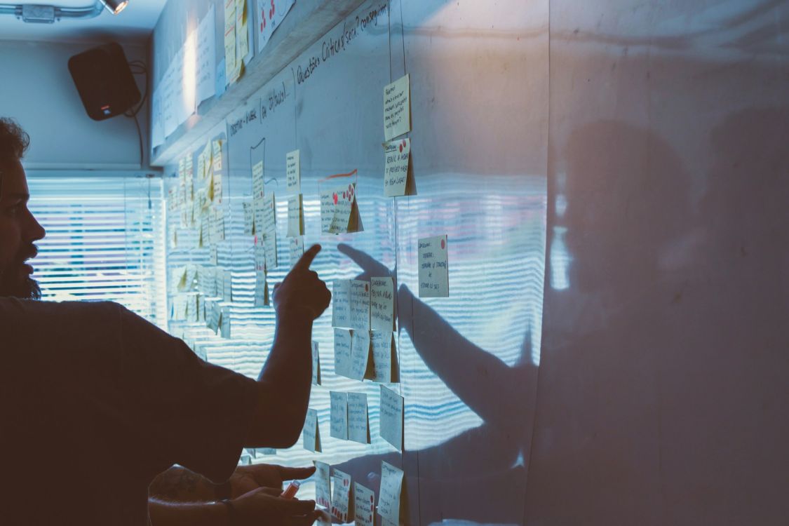Person, die auf Post-its an der Wand zeigt