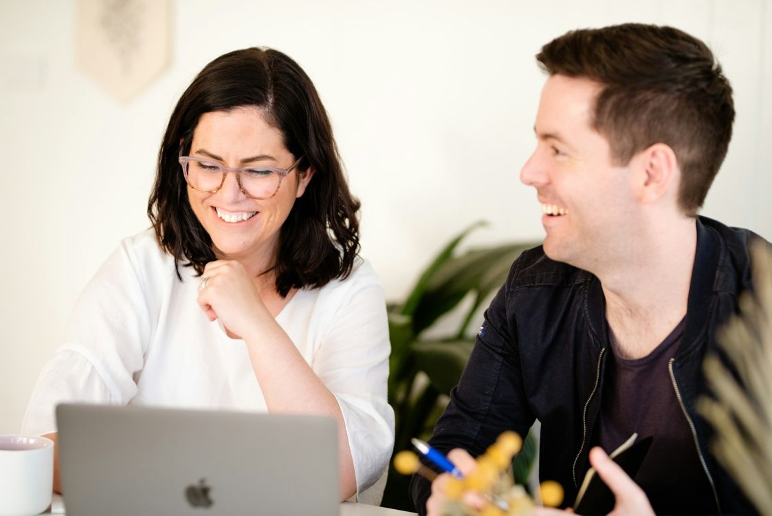 Ein Mann und eine Frau schauen fröhlich auf einen Laptop