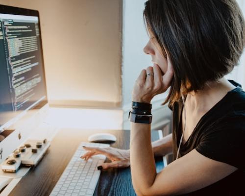 Frau sitzt am PC und programmiert einen Code