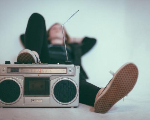 Mensch liegt auf dem Rücken hinter einem alten Radiogerät