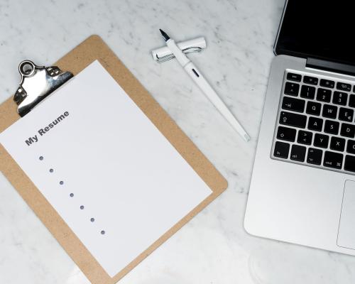 Leerer Lebenslauf neben Laptop und Füller auf dem Schreibtisch liegend